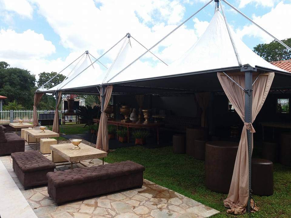 Tendas com lounge e mesas montadas em área gramada