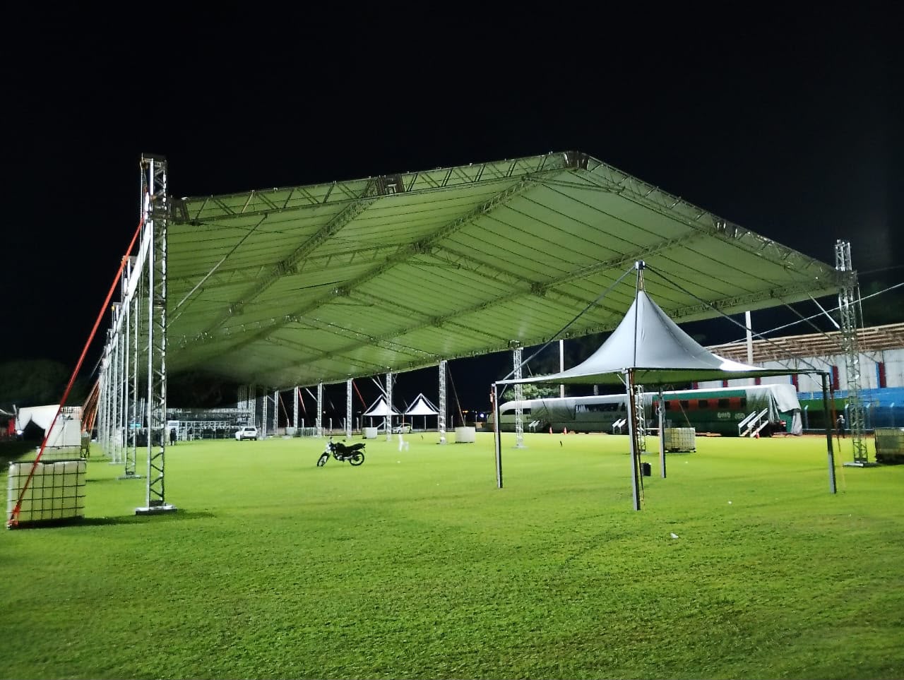 Estrutura coberta em box truss iluminada à noite em campo aberto